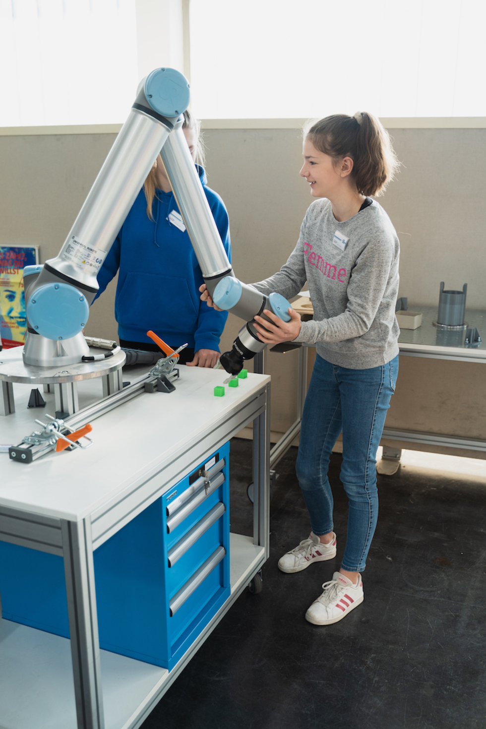 Zwei Mädchen bedienen einen Roboterarm